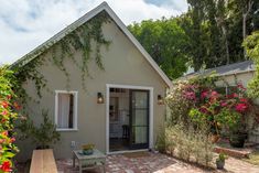 a small house with flowers growing on it's side and patio area next to the front door