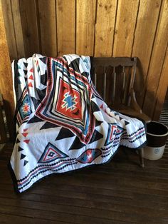 a blanket sitting on top of a wooden bench next to a cup and potted plant