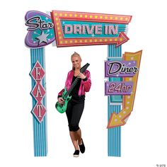 a woman holding a guitar under a drive in sign