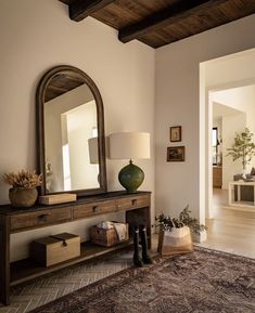 a living room with a large mirror on the wall next to a table and lamp