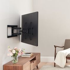 a living room with a tv mounted on the wall next to a table and chair