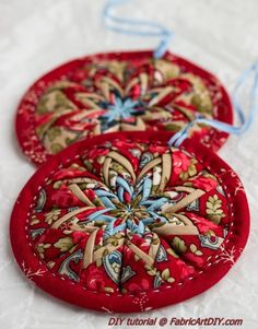 two red ornaments are sitting on a white tablecloth with blue string attached to them