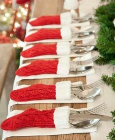 the table is set with silverware and red mittens on it, along with forks and spoons