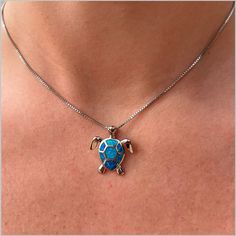 a woman wearing a necklace with a blue turtle on it's back and gold accents