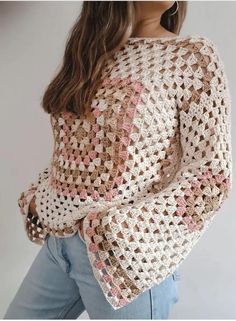 a woman is wearing a crocheted sweater with pink and white squares on it