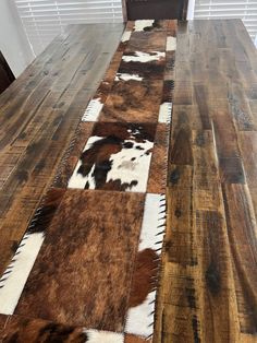 a wooden table topped with brown and white cow hide rugs on top of it