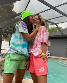 two girls standing next to each other in front of a pool