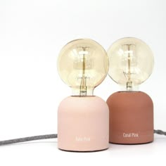 two pink and brown lamps sitting next to each other on a white surface with cord