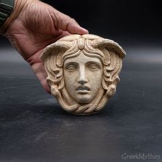 a hand is holding a carved stone head