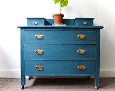 a blue dresser with two drawers and a potted plant on top