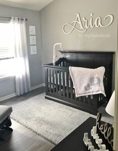 a baby's nursery room with a crib and name sign on the wall