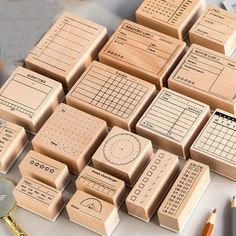 many wooden stamps are arranged on a table with some pencils and other items nearby