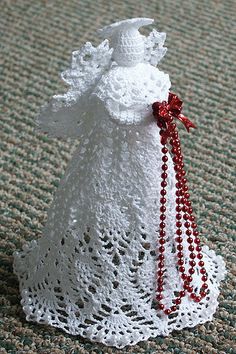 a white crocheted bag with red beads and a tassel on the side