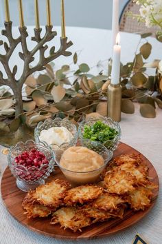 a wooden plate topped with fried food next to a candle and some candlesticks