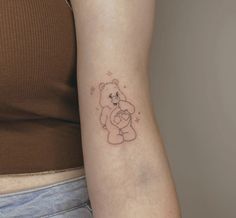 a woman with a tattoo on her arm holding a teddy bear in the shape of a heart