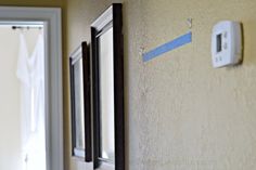 a wall with some blue tape on it next to a window and door frame in the background