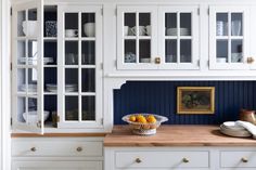 a kitchen with white cupboards and blue painted walls is pictured in this image, there are plates on the counter