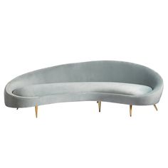 an oval shaped couch with gold legs and a gray velvet upholstered backrest