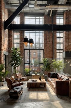 an industrial living room with exposed brick walls and floor to ceiling windows, leather couches and coffee table