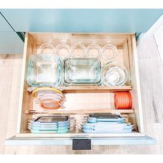 an open drawer filled with dishes and glasses