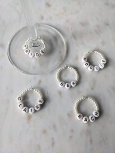 three wine glasses and four personalized beaded bracelets on a marble table with a wine glass in the background