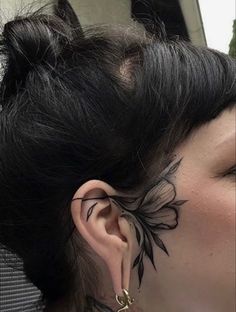 a woman with black ink on her face and ear is looking into the distance while wearing gold hoop earrings