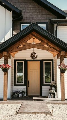 a white house with black doors and two planters on the front porch, along with potted flowers