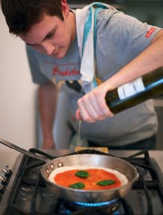 a man pouring wine into a pan on top of a stove with food in it