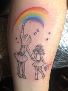 a couple holding hands with a rainbow in the sky and stars on their arm behind them