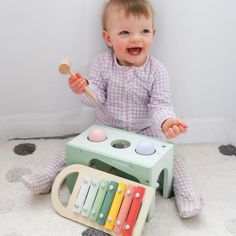 a baby sitting on the floor playing with an assortment of musical instruments in front of him