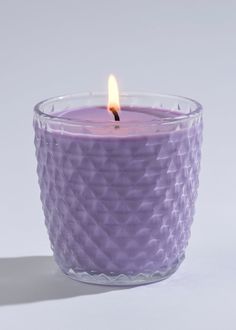 a purple candle with a single lit candle in front of it on a white background