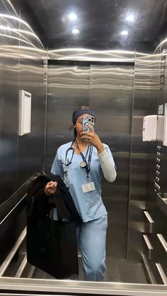 a woman in scrubs taking a selfie with her cell phone while walking down an escalator