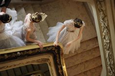 two women dressed in white are standing on the stairs and looking at their own reflection