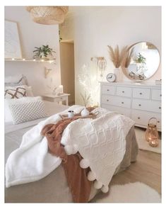 a bedroom with white furniture and lights on the wall, along with a bed covered in blankets