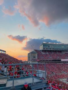 a stadium filled with lots of people sitting on bleachers and watching the sun set