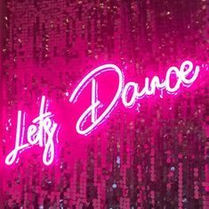 a neon sign that says let's dance on the side of a wall with sequins