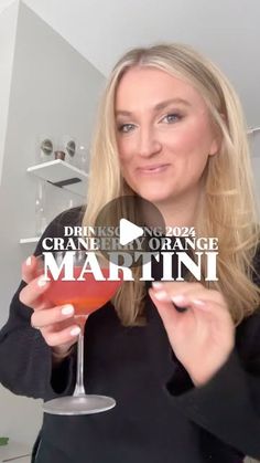 a woman holding up a drink in her hand and the words orange martini on it