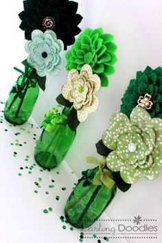 four green vases with flowers in them