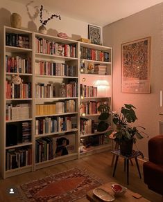 a living room filled with lots of books on top of a white book shelf next to a red chair