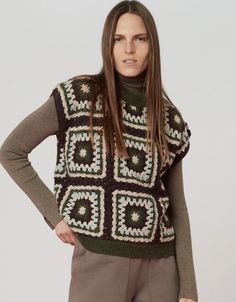 a woman is standing with her hands on her hips and wearing a sweater that has squares in the middle