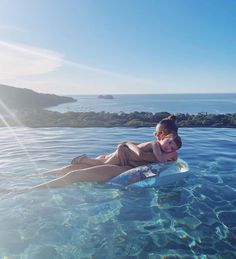 a woman laying on top of a surfboard in the water next to an island