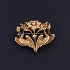 Art Nouveau Swan Brooch: This 10k gold brooch (circa 1910) features two swans on either side of a pearl studded flower.   The piece measures 0.9 inches by 1.1 inch wide and weighs 2.85 grams. It is in very good condition; however, the pin stem is slightly wavy and the pin catch was replaced at some point in the past.  Upon purchase, your brooch will arrive elegantly packaged, ready for gifting or as a special treat for yourself.  We carefully wrap each piece to ensure a delightful unboxing experience. We also offer free and flexible layaway plans, so take advantage of this option to make owning your dream piece even more achievable. + Trademark Antiques Shop Homepage https://www.etsy.com/shop/TrademarkAntiques + Our Store Policies https://www.etsy.com/shop/TrademarkAntiques/policy?ref=shop Two Swans, Swan Brooch, Unboxing Experience, Gold Brooch, Gold Brooches, Antique Shops, Pearl Studs, 10k Gold, Brooch Pin