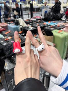 a person with two rings on their fingers in front of suitcases at an airport