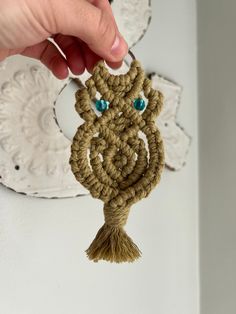 someone is holding up a crocheted keychain with an evil face on it