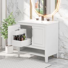 a bathroom vanity with an illuminated mirror above it and a potted plant in the corner