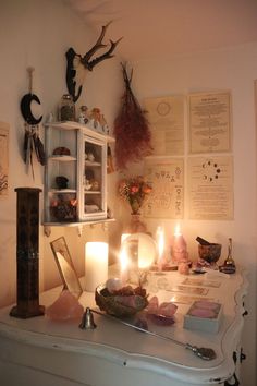 a table topped with lots of candles next to a wall filled with pictures and other items