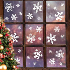 a christmas tree in front of a window with snowflakes on it