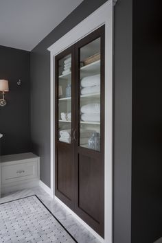 a bathroom with gray walls and white tile on the floor, along with dark wood doors