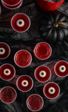 many red cups are lined up on a black cloth with pumpkins in the background