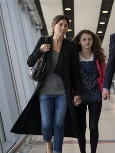 two women walking down an escalator with one holding the hand of another woman